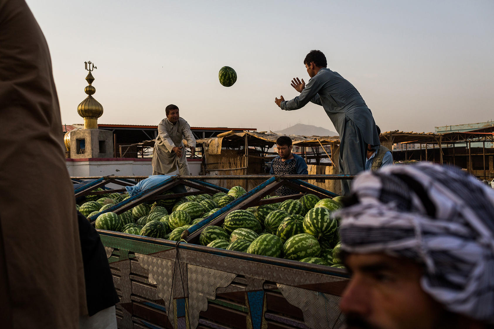 Farmers unload melons at the melon market in Kabul, Aug. 8, 2017. As bountiful as the fruit is this season, the Taliban and militias defending the government against it have taken a toll on farmers and traders. (Jim Huylebroek/The New York Times) 