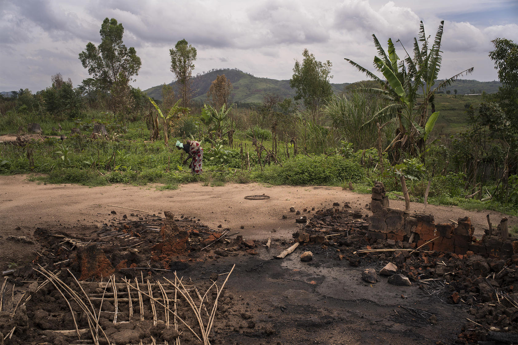 A woman salvages crops near the charred remains of her home, burned amid Ituri’s warfare in 2018. A quarter of the province’s population has been forcibly uprooted in more than 25 years of violence. (Diana Zeyneb Alhindawi/The New York Times)