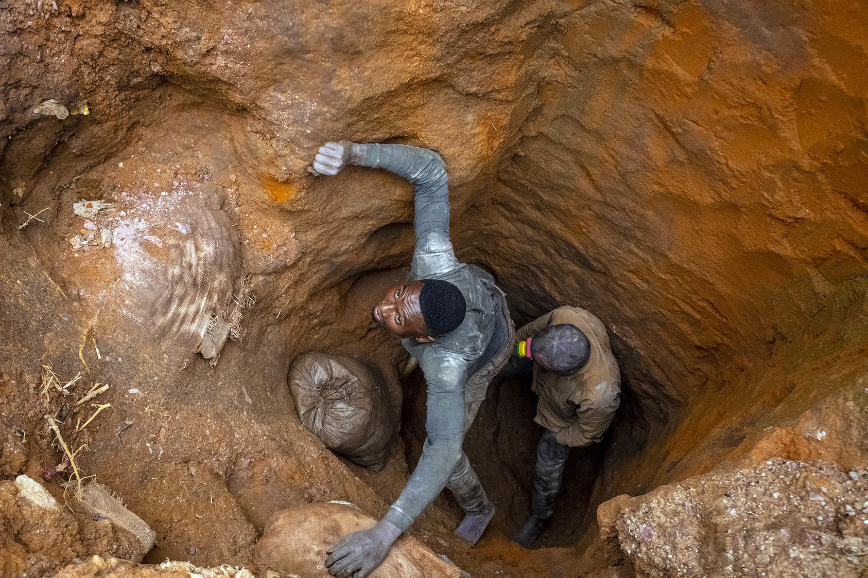 Jose Bumba, left, pulls a 220-pound bag of cobalt from a makeshift mine in Kasulo, the Democratic Republic of the Congo, on April 26, 2021. (Ashley Gilbertson/The New York Times)